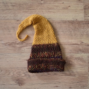 Peut inclure: Un chapeau tricoté avec un long sommet pointu et un schéma de couleurs brun et jaune.