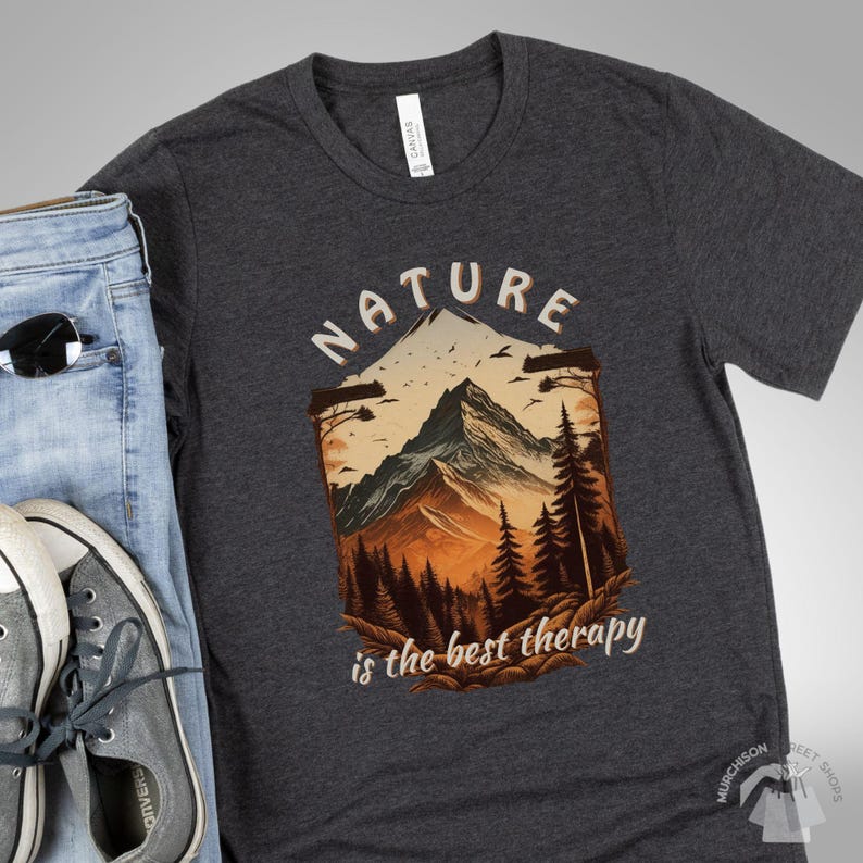 Forest Themed T Shirt Pine Tree Nature Shirt with a flat layout of a dark gray tshirt showing a mountain scene and the words Nature is the best therapy