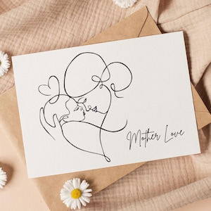 Pode incluir: Um cartão branco com um desenho a traço preto de uma mãe e uma criança em um abraço, com as palavras "Mother Love" em escrita cursiva. O cartão está em um envelope marrom, com um fundo de tecido bege e flores brancas.