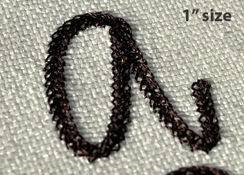 May include: Close-up of a dark brown, woven material forming a letter, approximately 1 inch in size. The material has a textured appearance, with the letter's shape clearly defined against a light-colored background. The text "1" size" is visible.