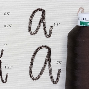 May include: A spool of dark brown Madeira thread next to embroidered letter "a" samples in various sizes: 0.5", 0.75", 1", 1.25", 1.5", and 1.75". The thread spool has a white label with green text.
