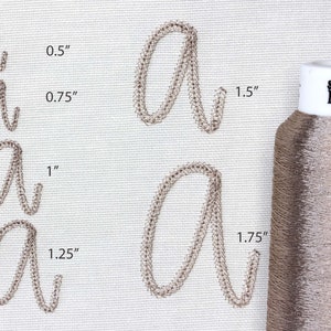 May include: Close-up of embroidered letter "a" in various sizes, ranging from 0.5" to 1.75", with a spool of metallic thread. The thread is labeled "Smooth Metallic". The embroidery is in a cursive style.