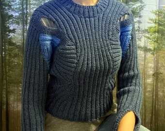 May include: A blue knitted sweater with a unique design featuring cutouts and blue accents. The sweater has a ribbed texture and a relaxed fit.