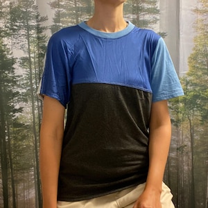 May include: A short-sleeved t-shirt with a blue, black, and light blue color block design. The shirt has a crew neck and a relaxed fit.
