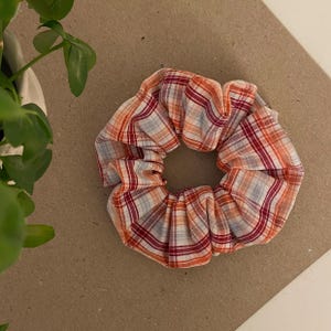 May include: A red, white and orange plaid scrunchie hair tie.