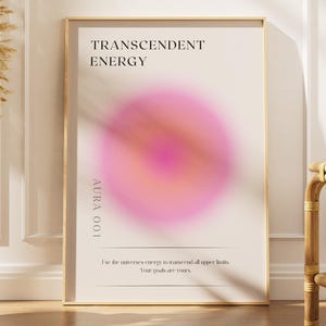 May include: A framed print with the words "TRANSCENDENT ENERGY" and a pink and orange aura design. The print also includes the text "AURA 001" and a quote. A decorative vase with dried plants is to the left.