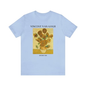 May include: Pale blue t-shirt displaying Vincent Van Gogh's "Sunflowers (1888)" painting. The image shows a vase of sunflowers in yellow and brown hues. The text "VINCENT VAN GOGH" and "SUNFLOWERS (1888)" are printed above and below the artwork.