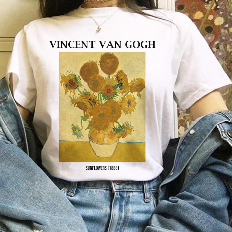 May include: White t-shirt with a print of Vincent van Gogh's "Sunflowers" painting. The artwork shows a vase of sunflowers in yellow, orange, and green hues. The text "VINCENT VAN GOGH" and "SUNFLOWERS [1888]" are printed above and below the artwork.