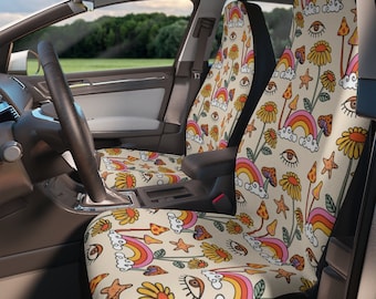 Puede incluir: Fundas de asiento de coche con un patrón repetido de arcoíris, setas, flores, estrellas y ojos en tonos naranja, rosa, amarillo y verde sobre un fondo beige. El interior del coche incluye un volante y una vista de un campo verde.