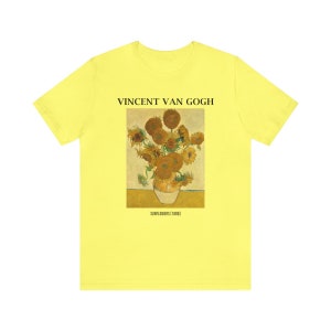 May include: A pale yellow t-shirt with a print of Vincent van Gogh's "Sunflowers (1888)". The artwork shows a vase of sunflowers in yellow, brown, and green. The text "VINCENT VAN GOGH" is above the artwork, with the title below.