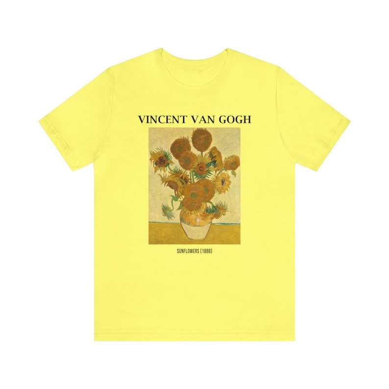 May include: A pale yellow t-shirt with a print of Vincent van Gogh's "Sunflowers (1888)". The artwork shows a vase of sunflowers in yellow, brown, and green. The text "VINCENT VAN GOGH" is above the artwork, with the title below.
