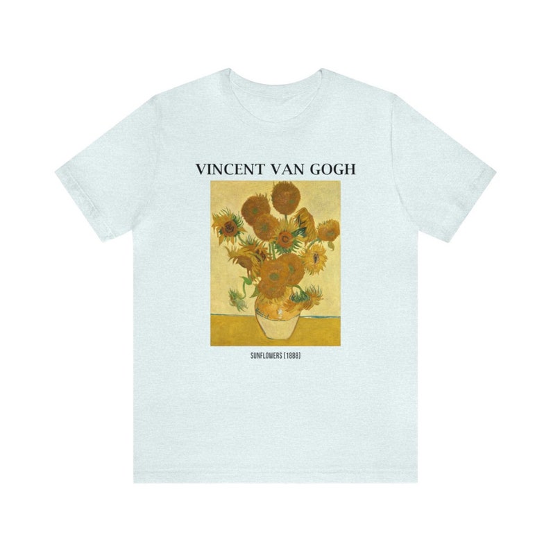 May include: Pale blue t-shirt with a print of Vincent Van Gogh's "Sunflowers" painting. The artwork depicts a vase of sunflowers in yellow and brown hues. The text "VINCENT VAN GOGH" and "SUNFLOWERS (1888)" are printed above and below the artwork.