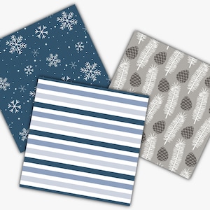 May include: Three square patterned papers. One has a navy blue background with white snowflakes. Another has blue and white horizontal stripes. The third has a gray background with white pine needles and brown pine cones.