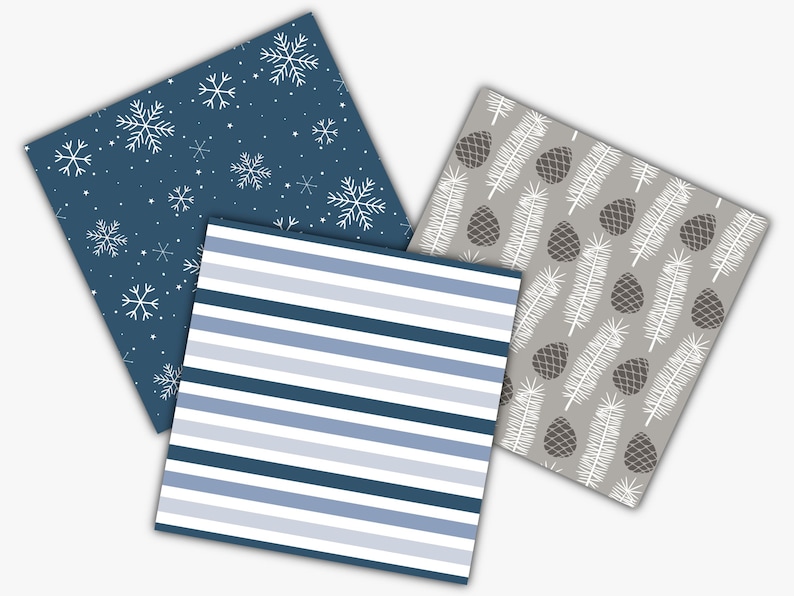 May include: Three square patterned papers. One has a navy blue background with white snowflakes. Another has blue and white horizontal stripes. The third has a gray background with white pine needles and brown pine cones.