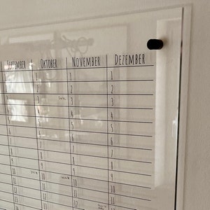 May include: A clear acrylic dry erase calendar with the months September, October, November, and December labeled. The calendar has lines for each day of the month and is designed to be hung on a wall.