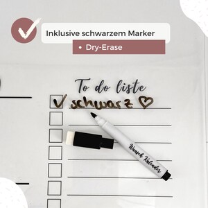May include: White dry-erase calendar with a to-do list that says "To do liste schwarz" with a heart drawn next to it. A black dry-erase marker is on top of the calendar with the words "Wunsch Kalender" written on it. A black eraser is next to the marker.