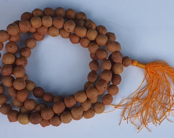 May include: A brown wooden mala bead necklace with a tassel made of orange thread.