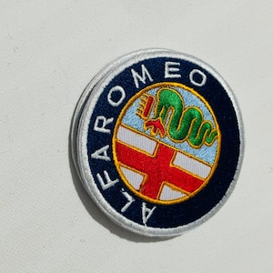 May include: An embroidered patch featuring the Alfa Romeo logo. The logo is blue and white with a red cross, a green snake, and the words "Alfa Romeo" in a white circle.