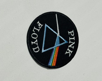 Op de afbeelding: Een geborduurde zwarte en witte patch met een driehoek en een regenboog. De tekst "PINK FLOYD" staat rond de rand van de patch.