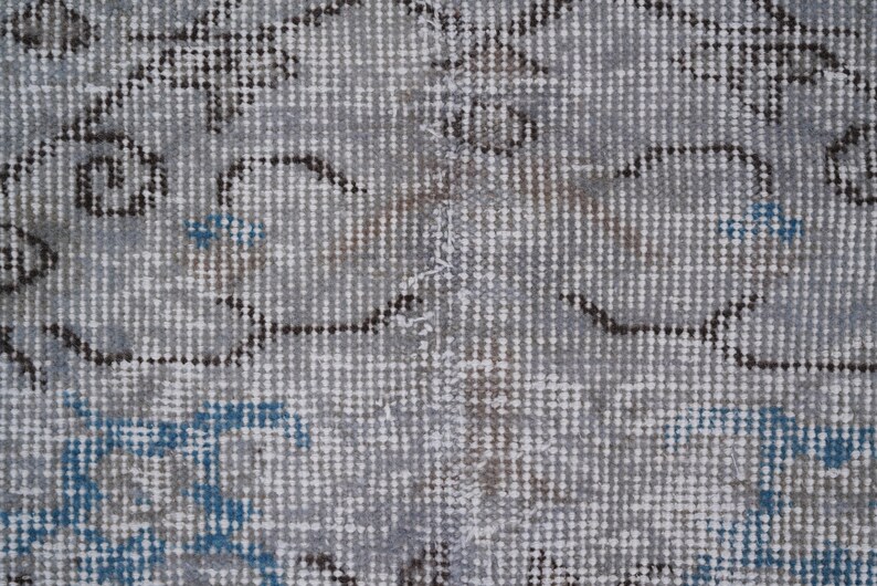 May include: Close-up of a gray and white patterned rug with blue accents. The rug has a woven texture and a subtle distressed look.