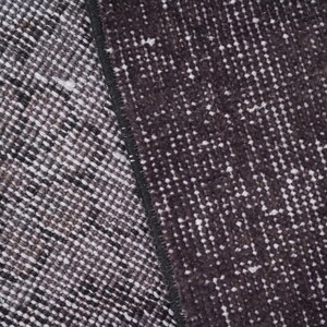 Puede incluir: Primer plano de una secci&oacute;n de una alfombra estampada en gris oscuro y blanco. La alfombra tiene un aspecto texturizado con un patr&oacute;n repetitivo de peque&ntilde;as formas irregulares. La paleta de colores es principalmente gris oscuro y blanco.