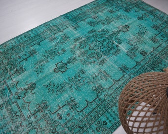 May include: A vintage teal blue rug with a faded, intricate floral pattern. The rug has a distressed look with a worn, faded appearance.