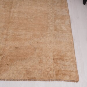 May include: A light brown rug with a subtle pattern. The rug has a fringed edge and is made of a soft, woven material.