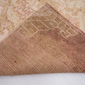 May include: Close-up of the back side of a beige and brown rug with a woven texture.