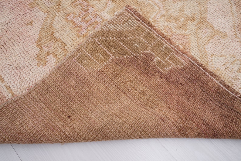 May include: Close-up of the back side of a beige and brown rug with a woven texture.
