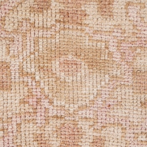 May include: Close-up of a beige and pink woven rug with a textured surface. The rug has a subtle pattern of small, repeating shapes.