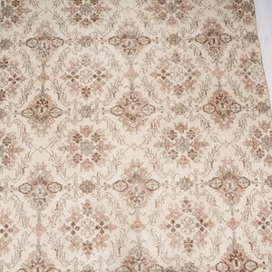 Peut inclure: Un tapis de couleur cr&egrave;me avec un motif floral brun et beige qui se r&eacute;p&egrave;te.