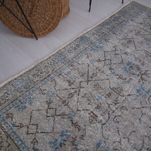 May include: A vintage rug with a faded blue and gray color scheme. The rug has a geometric pattern with intricate details. The rug is perfect for adding a touch of traditional style to any room.
