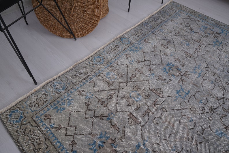 May include: A vintage rug with a faded blue and gray color scheme. The rug has a geometric pattern with intricate details. The rug is perfect for adding a touch of traditional style to any room.