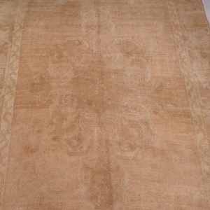May include: A light brown rug with a subtle pattern. The rug has a worn, vintage look and is made of a soft, natural material.
