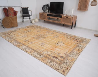 Può includere: Un tappeto rettangolare dall'aspetto invecchiato, con un campo giallo dorato e un bordo dettagliato. Il tappeto presenta motivi floreali e geometrici nei toni del marrone e del crema, creando un'estetica vintage. Il tappeto è posato su un pavimento bianco.