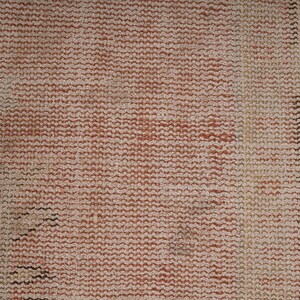 May include: Close-up of a woven fabric with a textured surface. The fabric is a light brown color with a subtle red hue. The weave is tight and uniform, creating a smooth, even surface.