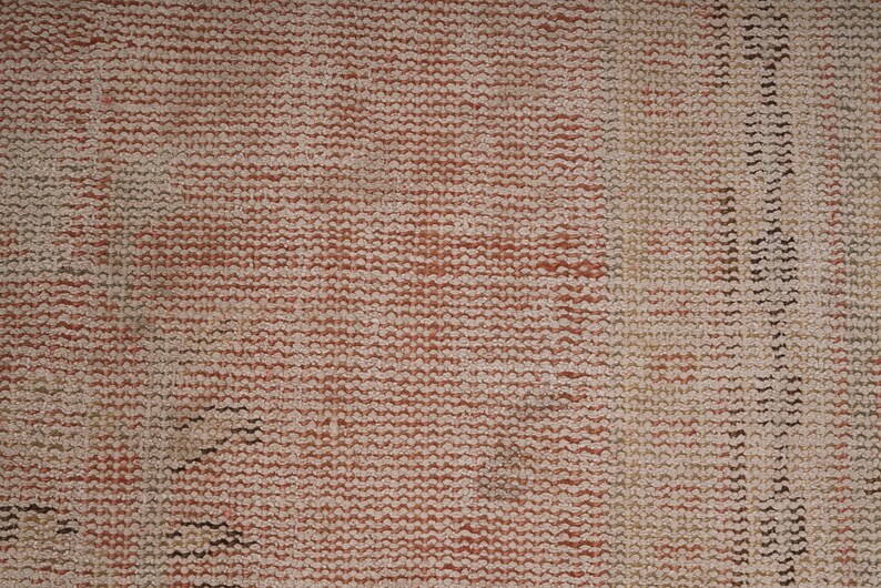 May include: Close-up of a woven fabric with a textured surface. The fabric is a light brown color with a subtle red hue. The weave is tight and uniform, creating a smooth, even surface.