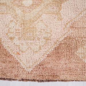 May include: Close-up of a beige and brown patterned rug with a textured surface. The rug has a geometric design with a faded appearance.