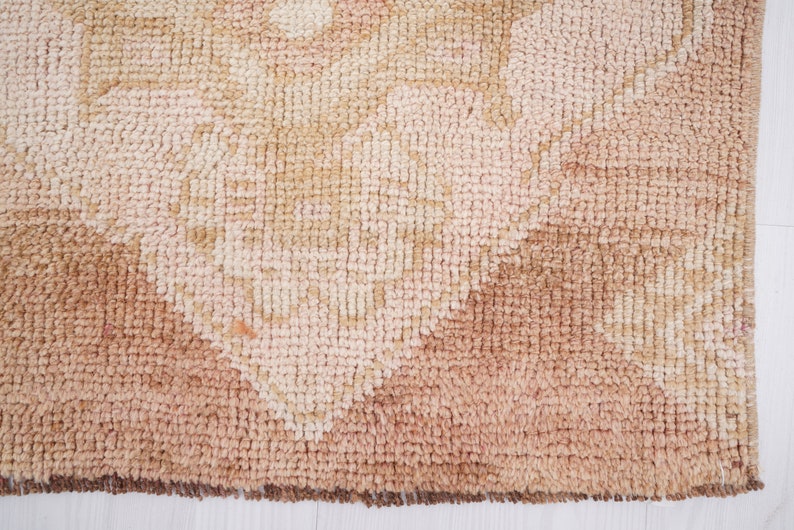 May include: Close-up of a beige and brown patterned rug with a textured surface. The rug has a geometric design with a faded appearance.