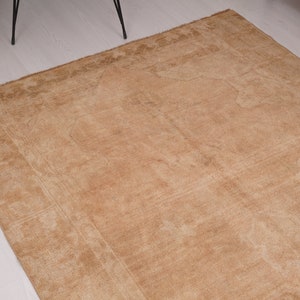 May include: A light brown rug with a subtle pattern. The rug has a worn, vintage look and is made of a soft, natural fiber.