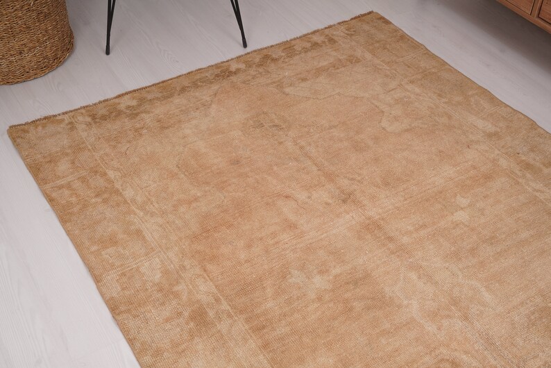 May include: A light brown rug with a subtle pattern. The rug has a worn, vintage look and is made of a soft, natural fiber.