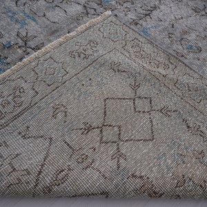 May include: Close-up of a light blue and brown patterned rug with a fringe border. The rug has a faded, vintage look.