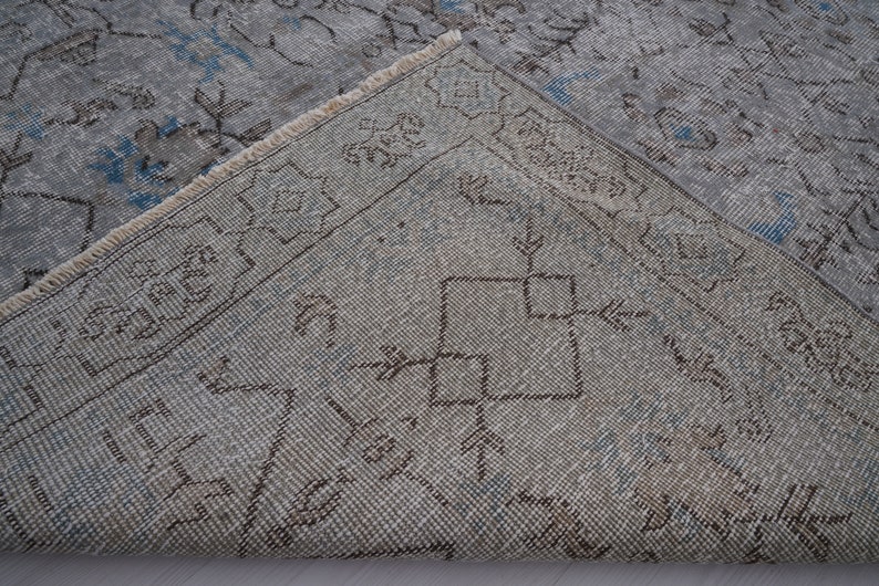 May include: Close-up of a light blue and brown patterned rug with a fringe border. The rug has a faded, vintage look.