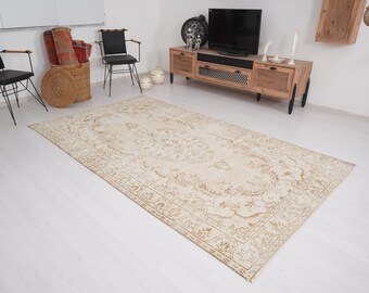 Op de afbeelding: Een rechthoekig, beige tapijt met een ingewikkeld bloemmotief. Het tapijt heeft een crèmekleurige achtergrond met een gedetailleerde rand en een centraal ontwerp in tinten bruin en beige. Het ligt op een witte vloer, ongeveer 300 cm lang.