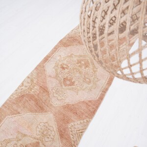 May include: A light brown runner rug with a geometric pattern. The rug has a faded, vintage look and is made of a soft, woven material.