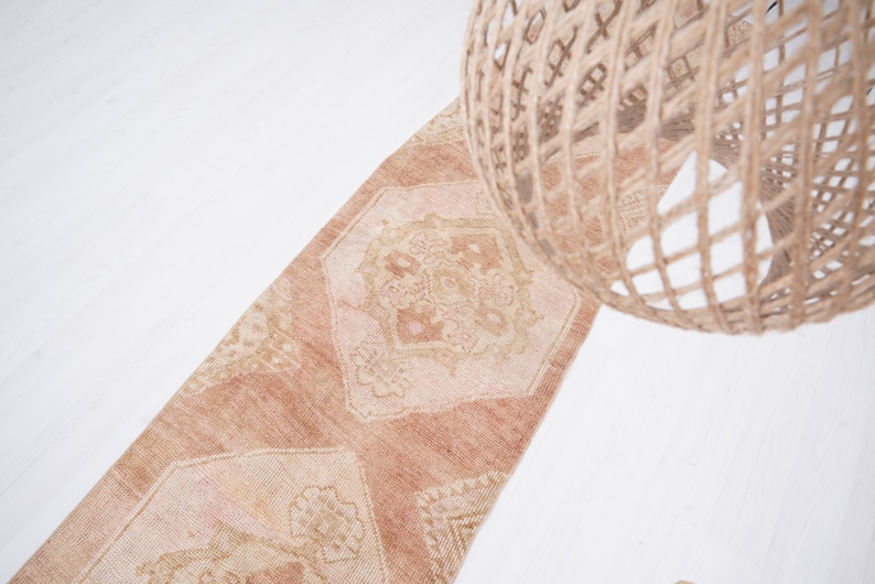 May include: A light brown runner rug with a geometric pattern. The rug has a faded, vintage look and is made of a soft, woven material.
