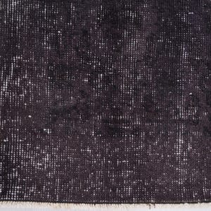 Puede incluir: Primer plano de una alfombra oscura y desgastada con una superficie texturizada. La alfombra tiene una combinaci&oacute;n de colores negro y gris con reflejos blancos, creando una apariencia vintage o antigua. Los bordes est&aacute;n deshilachados.
