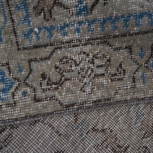 May include: Close-up of a gray and blue patterned rug with a fringe border. The rug has a traditional design with intricate details.