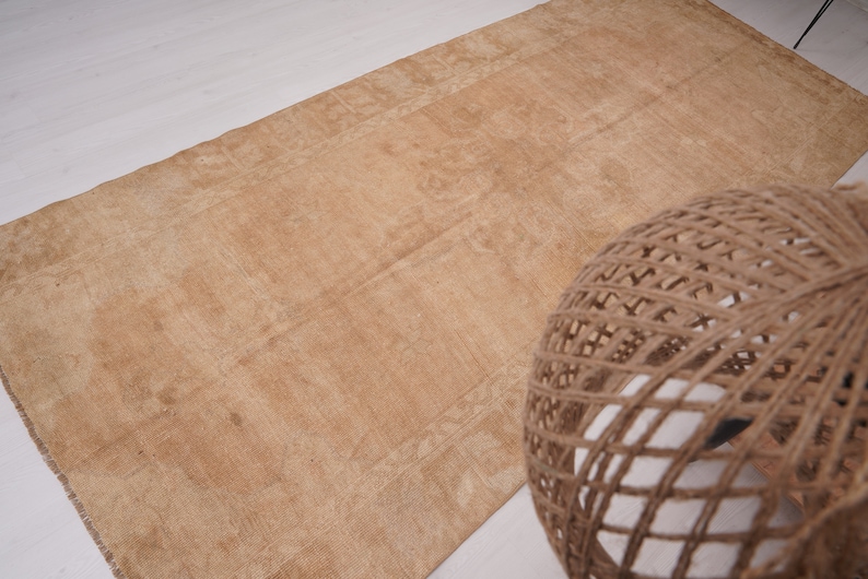 May include: A light brown rug with a subtle pattern. The rug is made of natural fibers and has a rustic look.