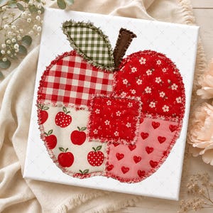 May include: A square canvas featuring a fabric apple appliqué made from various red and white patterned patches. The apple includes sections of red gingham, red floral print, red hearts on pink, and red apples on cream fabric with frayed edges.